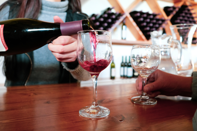 worker pouring a glass of red wine at a tasting room